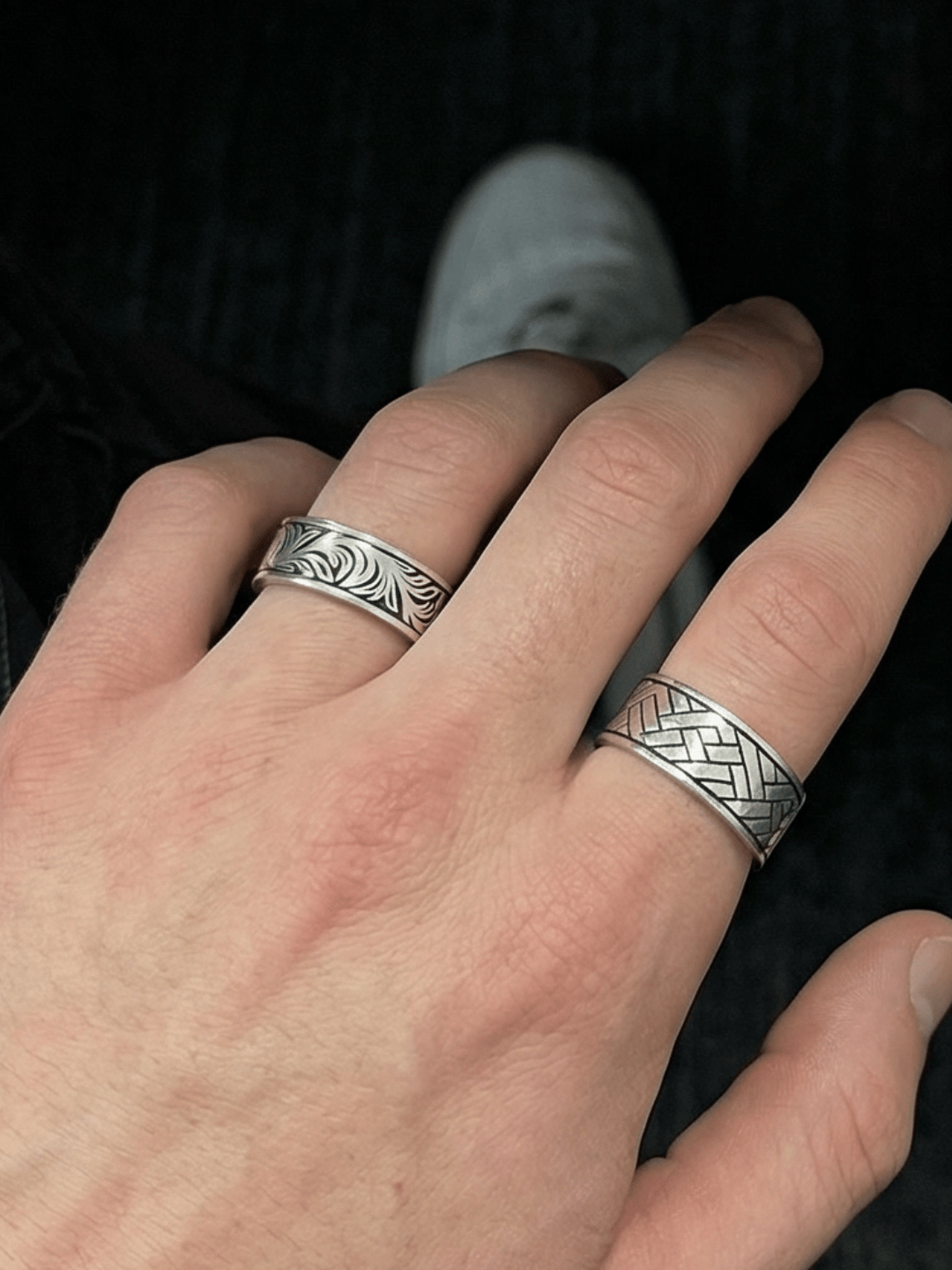 Foto auf dem Der silent garden Ring am Ringfinger getragen wird und der Linear Wave Ring am Zeigefinger getragen wird. Fokus auf dem Silent Garden Ring