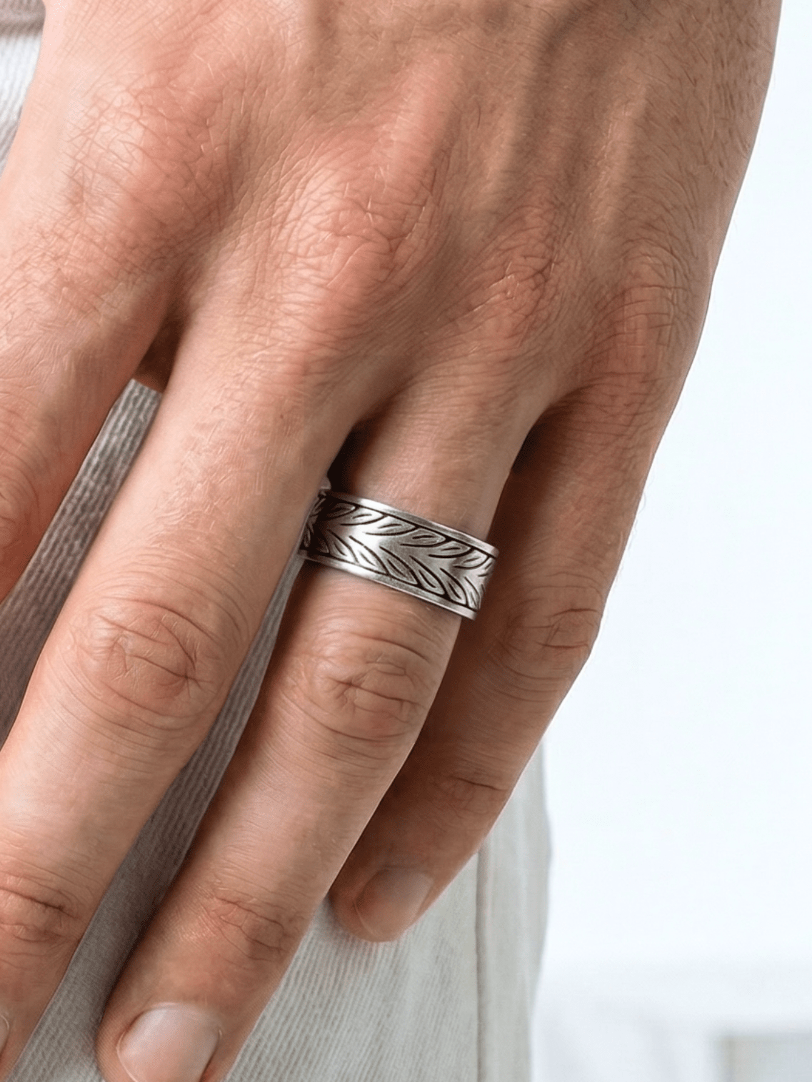 Der Coryngs Twin Leafs Ring am Ringfinger von einer Hand, die mit dem Daumen in der Hosentasche steckt Close up auf Ring